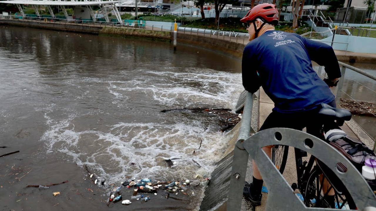 A cyclist looks over a polluted catchment canal after heavy rain