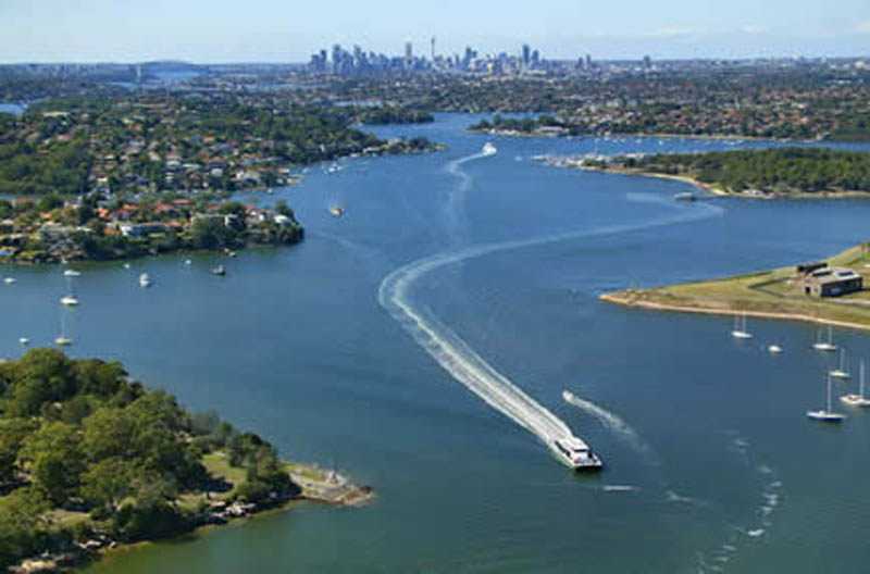 Aerial view of the Parramatta River with a ferry wake, looking toward the Sydney skyline
